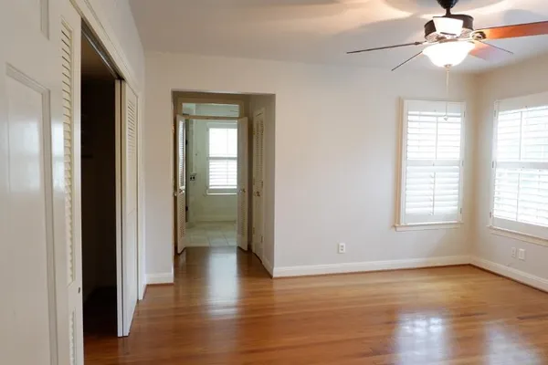 an empty room with wooden floor chandelier fan and windows