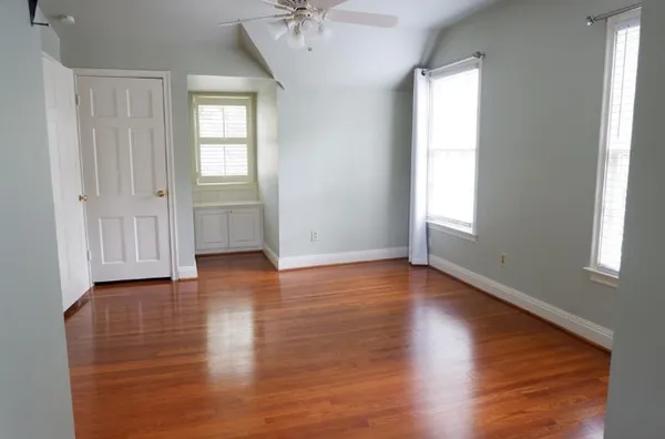 an empty room with wooden floor and windows