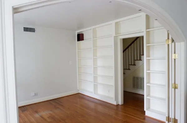 a view of an empty room with wooden floor and closet