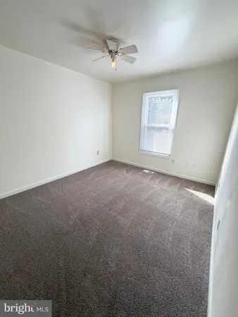 an empty room with a ceiling fan and window
