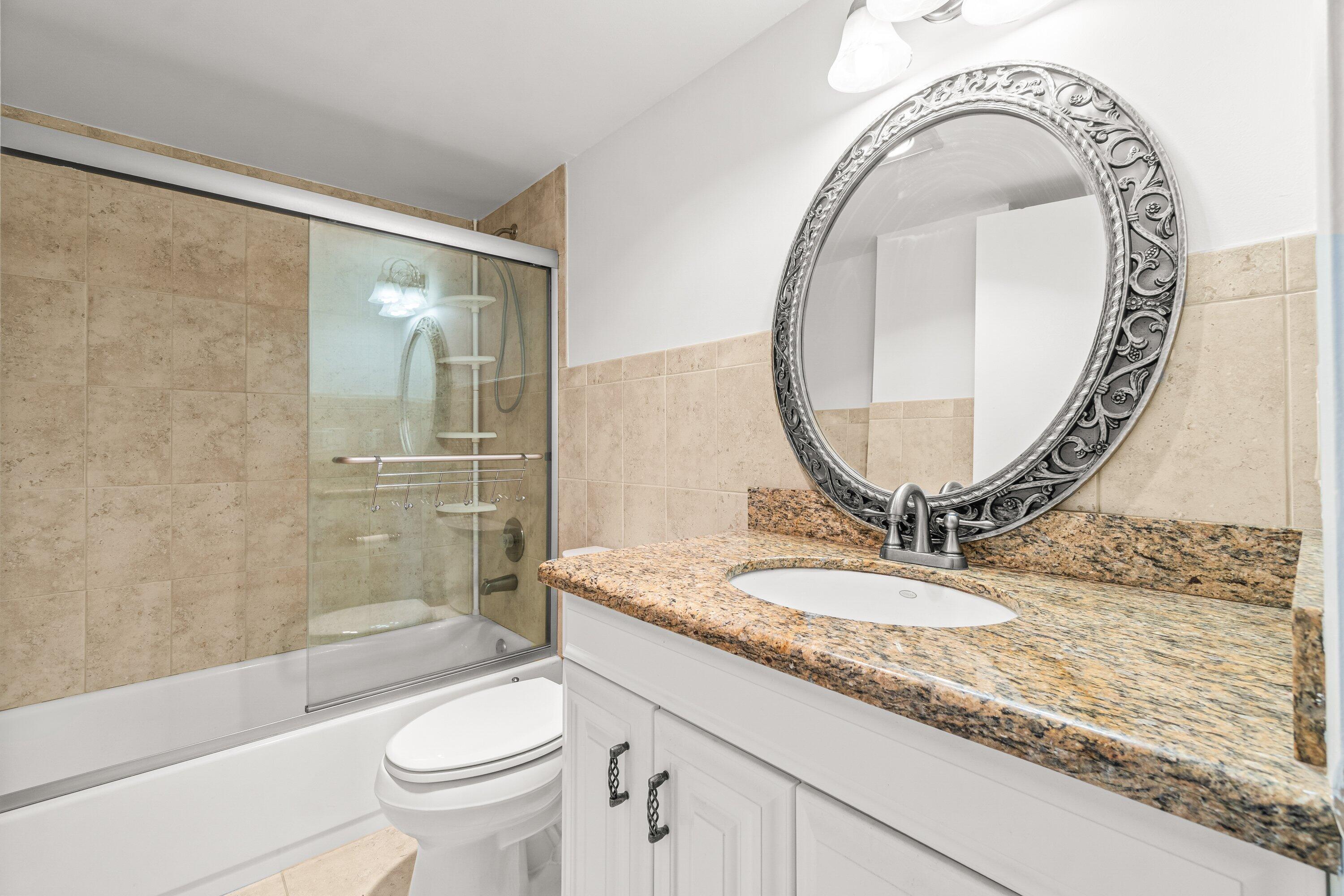 15 Royal Palm Way, Unit 604 Boca Raton, FL 33432 - Photo 15 of 41 a bathroom with a granite countertop toilet a sink and a mirror