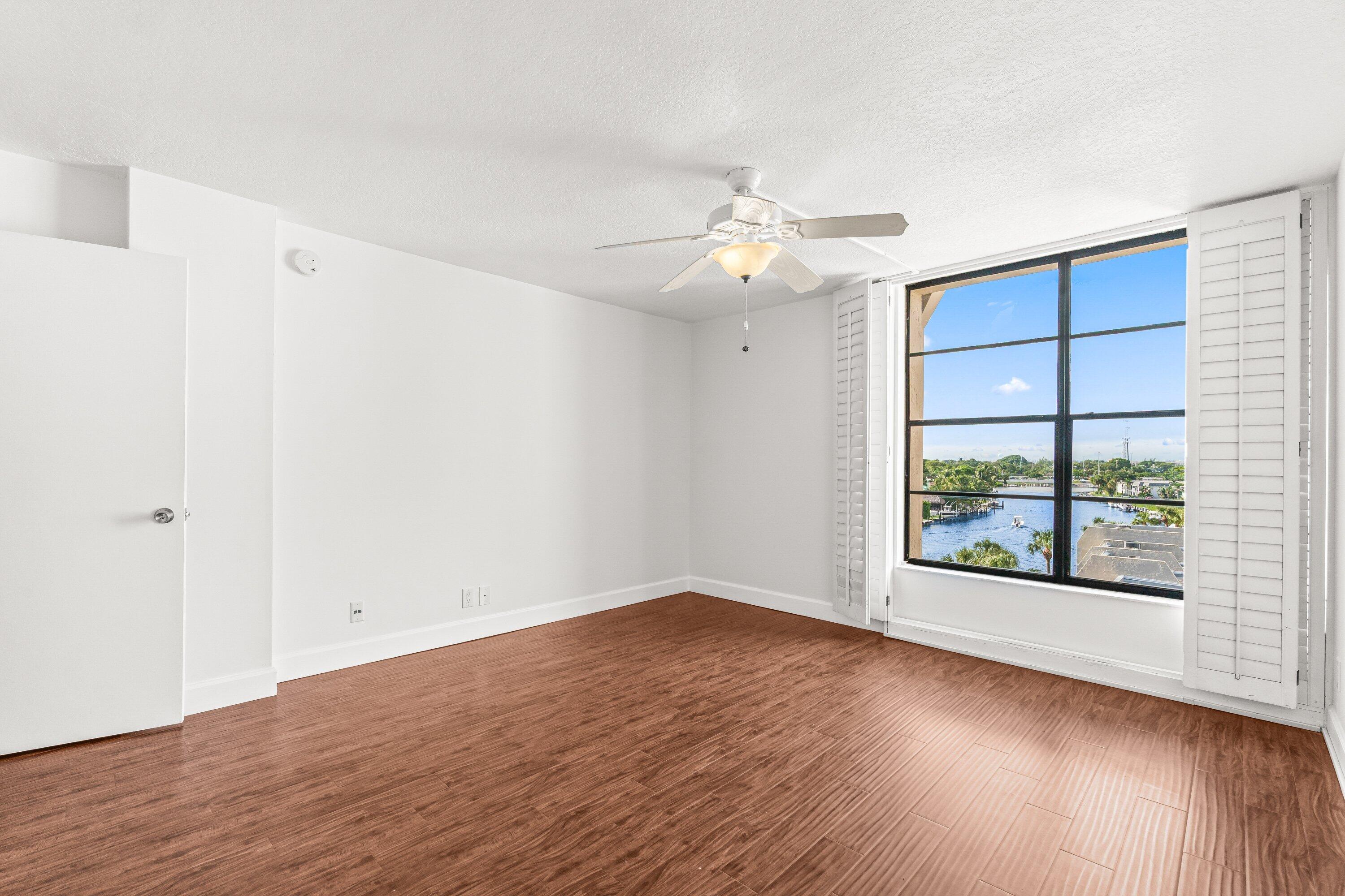 15 Royal Palm Way, Unit 604 Boca Raton, FL 33432 - Photo 19 of 41 an empty room with wooden floor chandelier fan and windows
