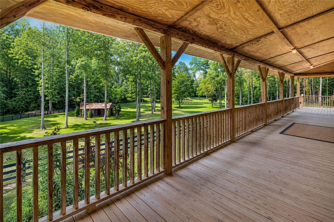 414 Devon Way Anderson, SC 29621 - Photo 43 of 50 A spacious wooden porch offers tranquil views of a secluded, tree-lined landscape with a rustic outbuilding.