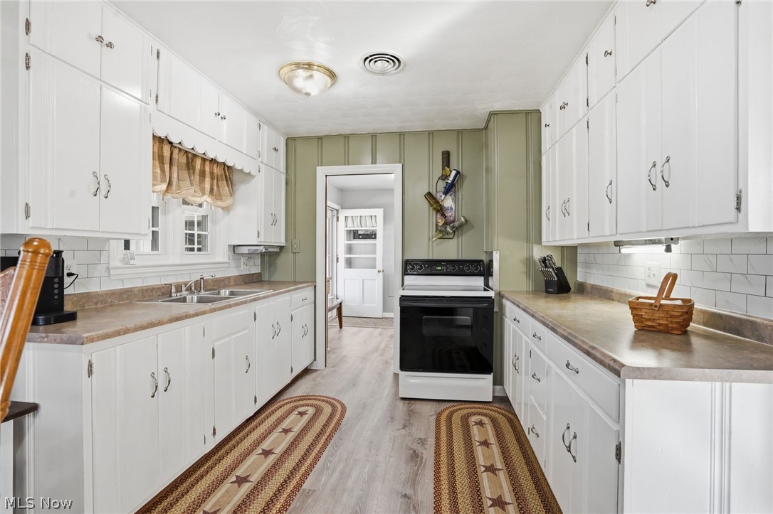 6655 Ceramic Road Crooksville, OH 43731 - Photo 6 of 34 Kitchen with electric range, decorative backsplash, white cabinets, and light wood-type flooring