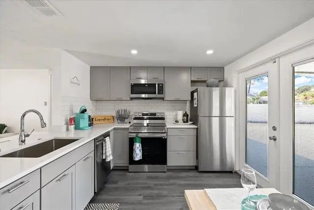 a kitchen with stainless steel appliances granite countertop a refrigerator sink and white cabinets