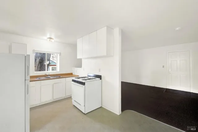 a kitchen with granite countertop white cabinets and a stove