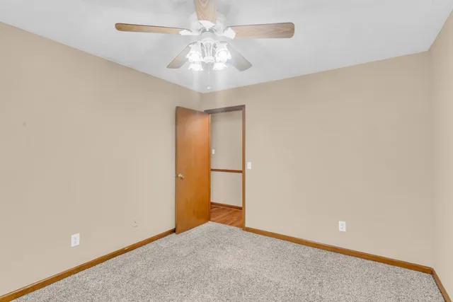 an empty room with a chandelier fan and windows