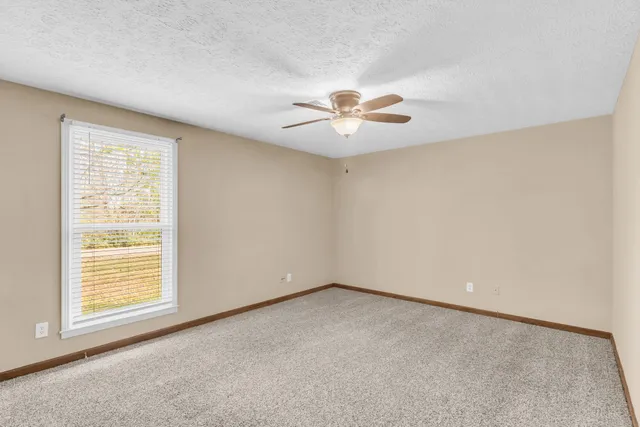 an empty room with a window and a ceiling fan