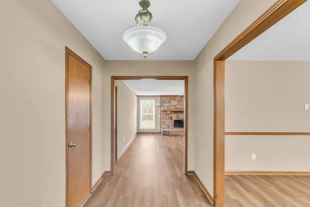 a view of a hallway with wooden floor and a bathroom