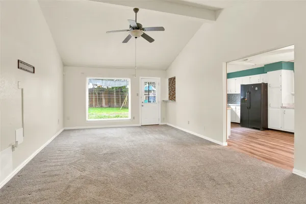 an empty room with chandelier fan and windows