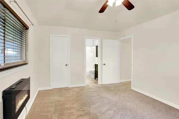 a view of an empty room with chandelier fan and fire place