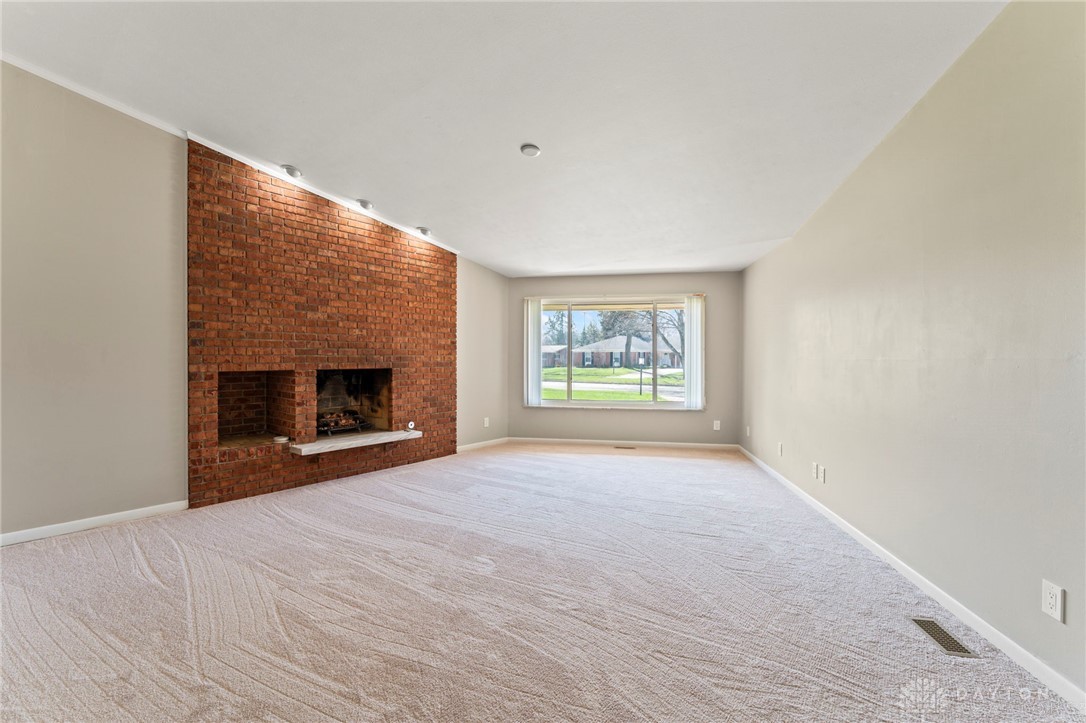 2247 East Whipp Road Dayton, OH 45440 - Photo 12 of 52 This living room features a captivating brick fireplace and a large window providing views of the neighborhood.
