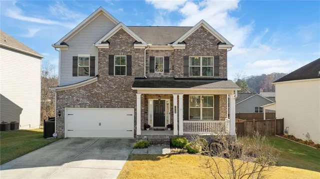 a front view of a house with yard and parking