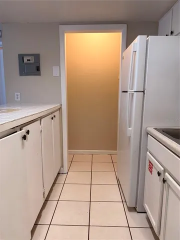 a view of a refrigerator in kitchen and a sink a window
