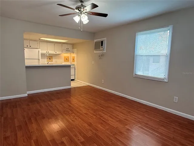 a view of empty room with wooden floor and fan