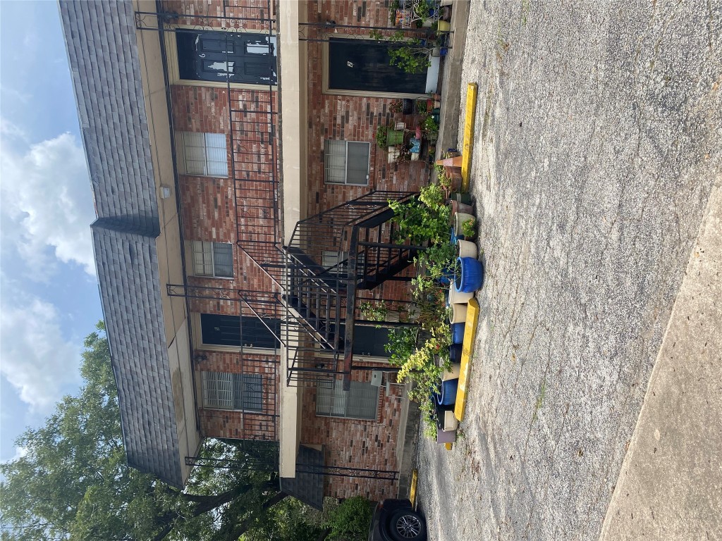 1601 Enfield Road, Unit 5 Austin, TX 78703 - Photo 17 of 20 View of front facade featuring brick siding, a shingled roof, uncovered parking, mansard roof, and a balcony