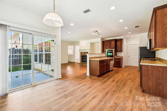 a open kitchen with stainless steel appliances granite countertop a stove top oven a refrigerator a sink and dishwasher with wooden floor