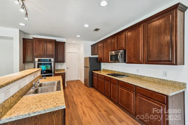 a kitchen with stainless steel appliances granite countertop wooden cabinets a stove and a sink