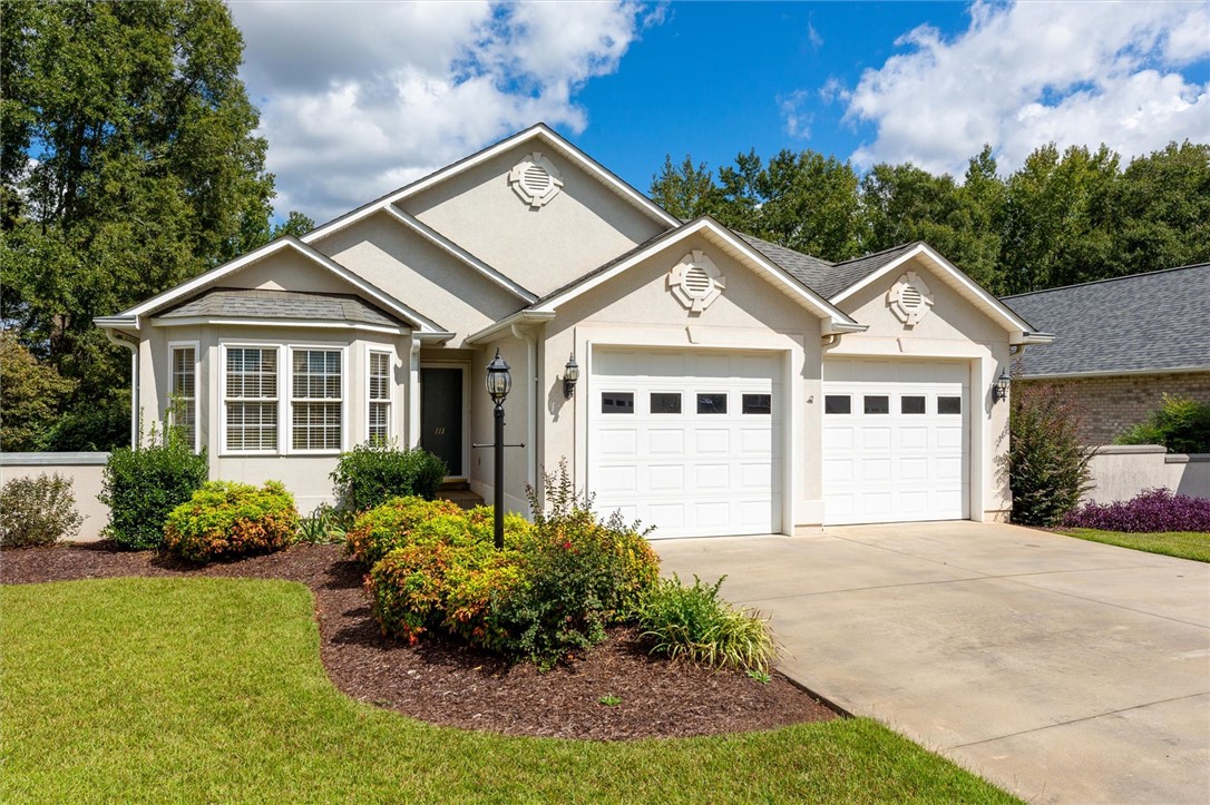 This residence features a well-maintained exterior, a concrete driveway, and attached garages.