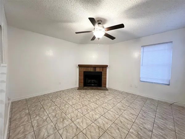 a view of an empty room with chandelier fan and fire place