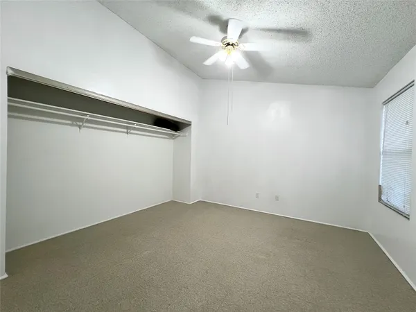 an empty room with a ceiling fan and window