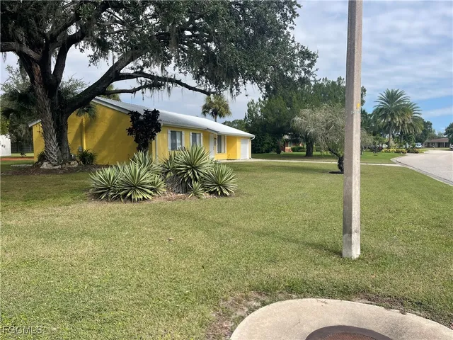 a backyard of a house with table and chairs under an umbrella