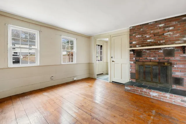 an empty room with wooden floor and fireplace