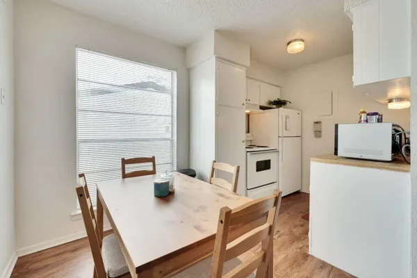 a kitchen with stainless steel appliances granite countertop a stove a refrigerator a dining table and chairs