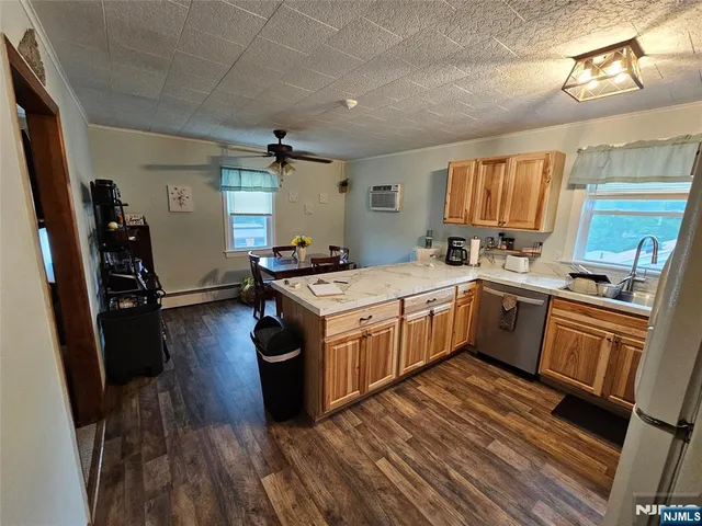 a kitchen with a sink appliances wooden floor and a window