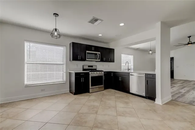 a kitchen with stainless steel appliances granite countertop grey cabinets a stove a sink and dishwasher