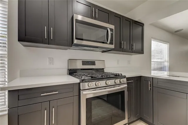 a large kitchen with a large counter top a sink stainless steel appliances and cabinets