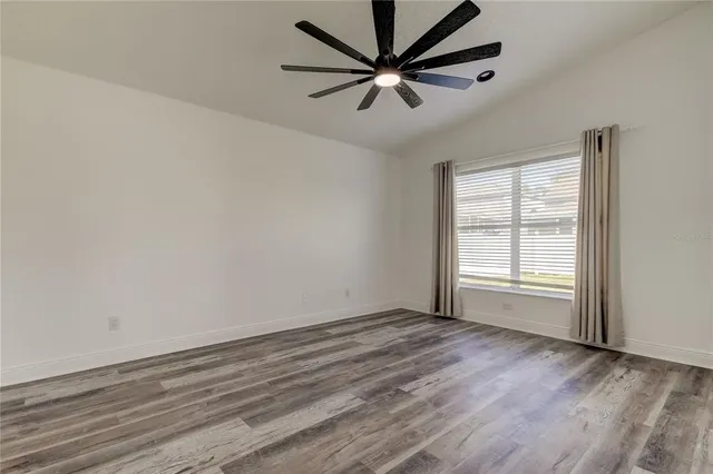 an empty room with wooden floor closet and fan