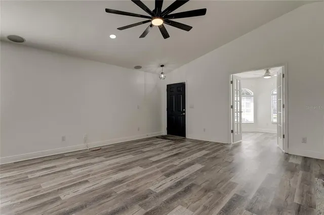 an empty room with wooden floor and windows