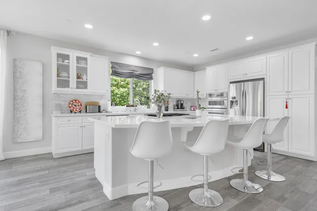 a kitchen with stainless steel appliances granite countertop a table and chairs in it