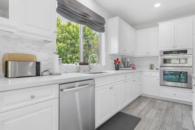 a kitchen with stainless steel appliances kitchen island granite countertop a stove a sink and white cabinets