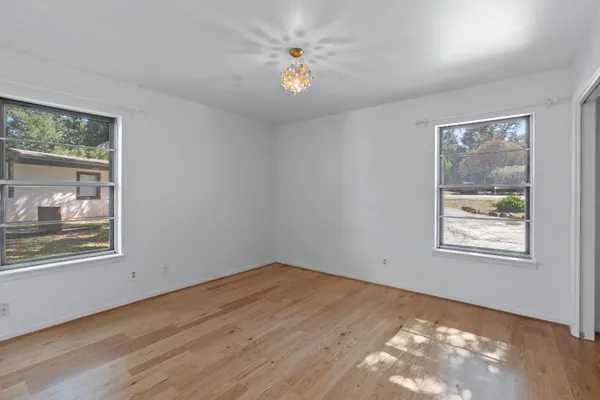 a view of an empty room with a window and wooden floor