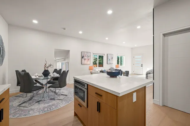 a view of kitchen island a sink wooden floor dining table and chairs