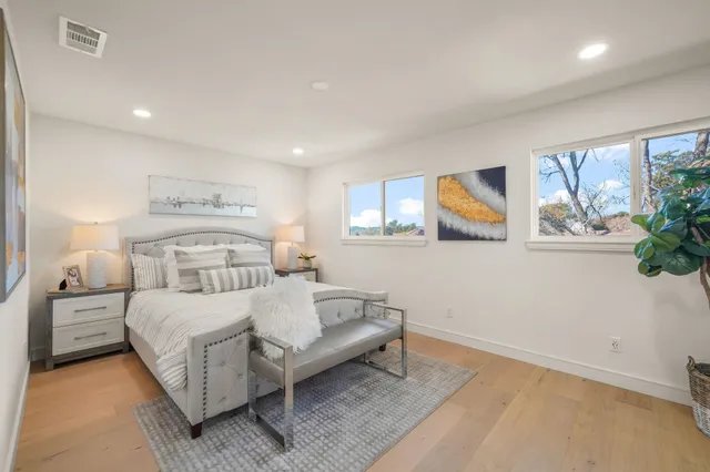a bedroom with a bed lamp and a large window
