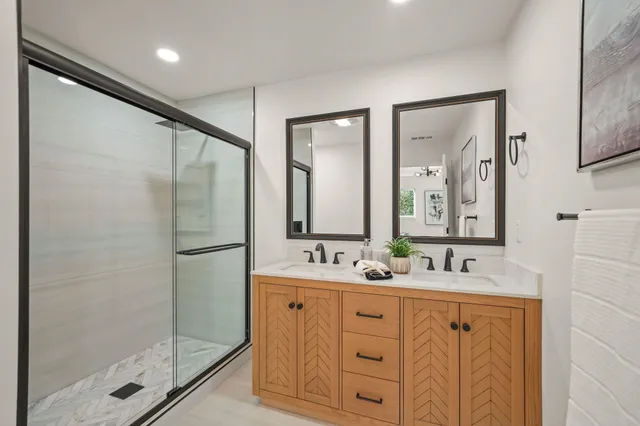a bathroom with a double vanity sink mirror and shower
