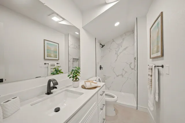 a bathroom with a sink a toilet and shower