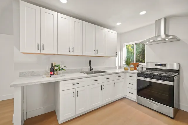 a kitchen with granite countertop white cabinets and stainless steel appliances
