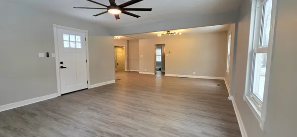 a view of an empty room with wooden floor and a window