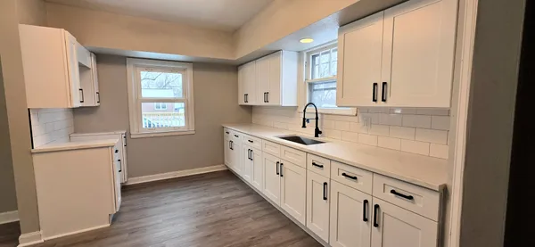 a large white kitchen with granite countertop a large window and a sink