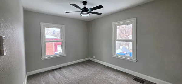 an empty room with windows and fan