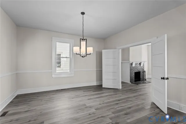 a view of empty room with wooden floor fireplace and window
