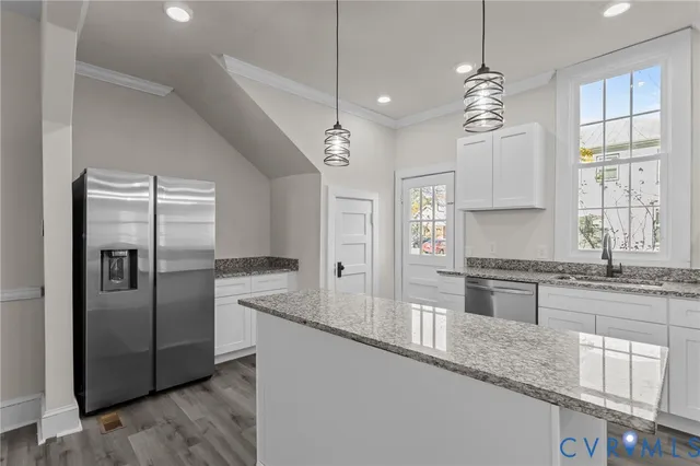 a kitchen with granite countertop a refrigerator a sink a center island and wooden floor