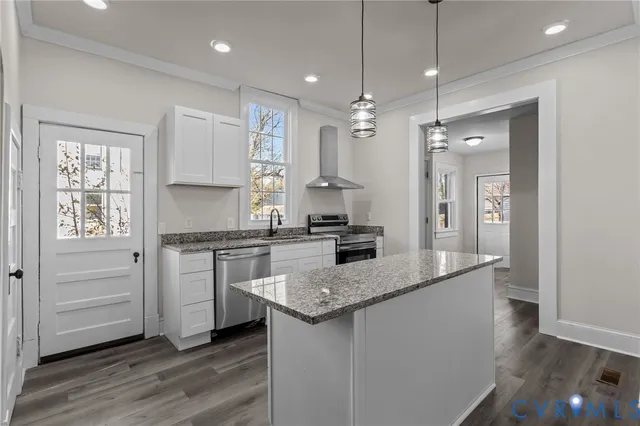 a kitchen with kitchen island granite countertop a sink appliances and cabinets