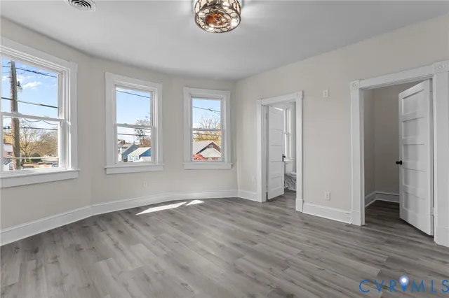 an empty room with wooden floor and windows