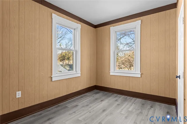 a view of an empty room with window and wooden floor