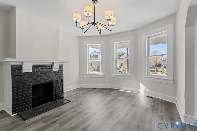 a view of an empty room with wooden floor fireplace and a window